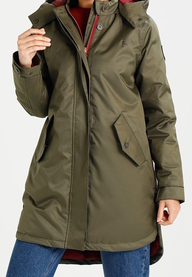 Parka imperméable vert olive avec une fermeture éclair et des boutons sur le devant, une capuche, des poches latérales et un doublure rouge. Présente une texture lisse et une coupe ajustée.