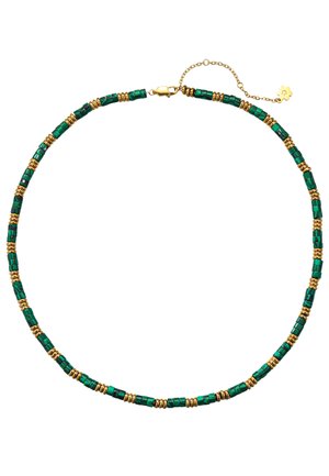 Frau mit silbernen Creolen, einer grünen und goldenen Perlenkette und einem trägerlosen Oberteil mit rosa, weißen und grünen Streifen.