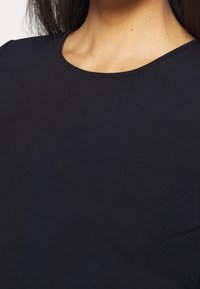 Zwarte kortebuiktop met een gladde textuur, voorzien van een ronde halslijn en een eenvoudig ontwerp, geschikt voor casual wear.