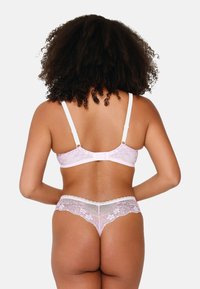 Set di lingerie in pizzo rosa composto da un bralette con spalline regolabili e chiusura a gancio, abbinato a pantaloni intimi in pizzo a modestia.