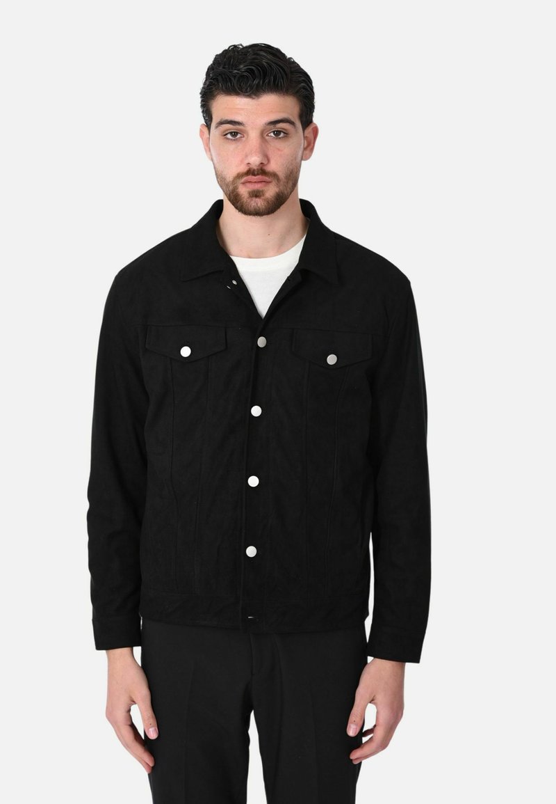 Giacca in suede nera con colletto a camicia, due tasche sul petto e chiusure con bottoni in argento. Il design è strutturato con una vestibilità su misura.