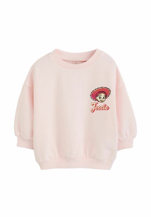 Jasnoróżowa dziecięca bluza z prążkowanymi mankietami i dołem, z obrazkiem kreskówkowej dziewczynki w czerwonym kapeluszu i słowem "Jessie" na piersi.