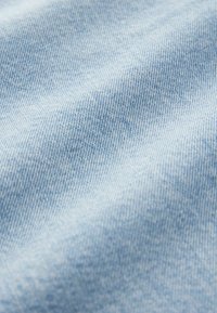 Lichtblau denim stof met een gladde textuur, met een strakke weving en subtiele variaties in schaduw over het oppervlak.