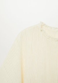 Pull tricoté couleur crème avec côtes verticales et petit col à volants sur fond blanc.