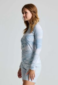 Langärmliges Sportshirt in Hellblau mit strukturiertem Muster. In Kombination mit passenden Shorts hat das Outfit einen enganliegenden Schnitt.