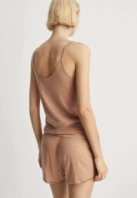 Lichtbruine mouwloze top en bijpassende shorts, gemaakt van zachte stof, met een ontspannen pasvorm en delicate kantafwerking op de shorts.