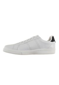 White leather sneaker with a rounded toe, flat white sole, and black heel accent. Features perforated stripes for ventilation. Lace-up design.