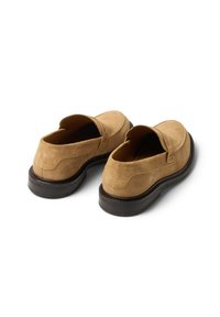 Beżowe mokasyny zamszowe na wsuwkę z zaokrąglonym noskiem, przeszyciami oraz ciemnobrązową gumową podeszwą. Minimalistyczny design bez widocznych elementów metalowych.