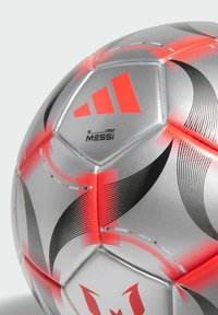Pallone da soccer argento con accenti rossi audaci, motivi neri curvi e dettagli di branding. Progettato con una superficie liscia e testurizzata.