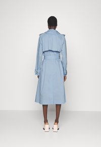 Jasnoniebieski płaszcz trench z paskiem w talii, długimi rękawami i naramiennikami. Długość do kolan, wykonany z gładkiego materiału.