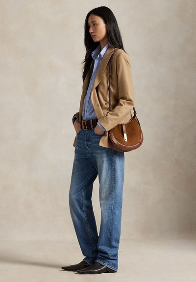 Béžový blazer, svetlomodrá košeľa, modré džínsy, hnedý opasok, hnedá kabelka cez plece a čierne špicaté topánky. Hladké textúry a prispôsobený strih.