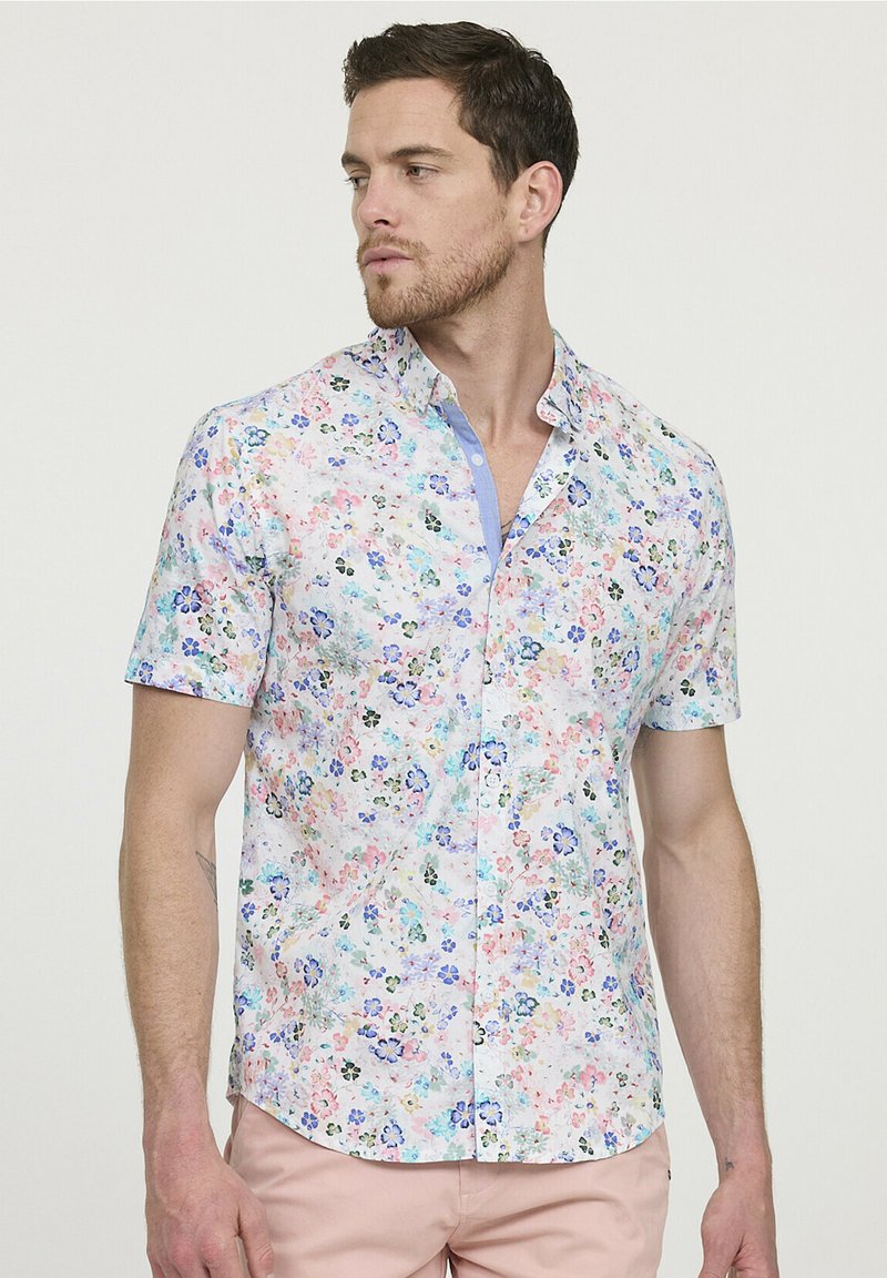 Korte mouwen overhemd met knoopsluiting in lichte stof, met een bloemenpatroon in roze, blauw en groen op een witte achtergrond.