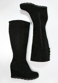 Botas de tacón cuña de ante negro hasta la rodilla con cremallera lateral, costuras decorativas texturizadas y un acabado suave en el tacón cuña.