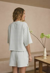 Light striped short-sleeve top and matching shorts in textured fabric. Colors include pale blue and white. Side slits visible on shorts.