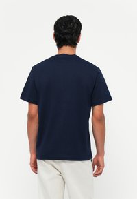Marineblauwe katoenen t-shirt met korte mouwen en een ronde hals. Opvallend detail: klein geborduurd logo op de linker mouw.