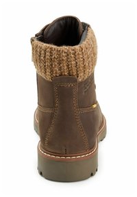 Bruine leren enkelboot met een gebreide beige boord. Beschikt over stikdetails en een robuuste zool voor extra grip.