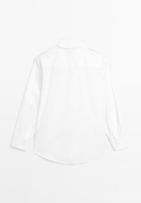 Hvid langærmet skjorte lavet af glat stof. Har en spids krave, knapmanchetter og en rund afslutning. Enkel og minimalistisk design.