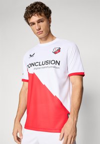 Weißes Trikot mit roten Akzenten und diagonaler Musterung. Verfügt über ein Logo, den Text "CONCLUSION" und kurze Ärmel. Hergestellt aus atmungsaktivem Stoff.