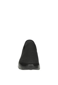 Le scarpe nere slip-on presentano una tomaia in mesh traspirante, una superficie testurizzata e una suola in gomma flessibile con una punta arrotondata.