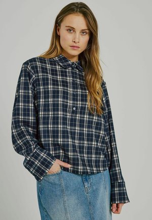 Marineblå och vit rutig skjorta med krage, långa ärmar och avspänd passform, kombinerad med ljust blå denimkjol.