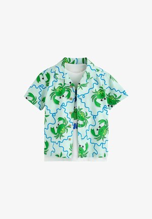 Modrá svetlomodrá košeľa s krátkym rukávom s motívom zelených kreslených krabov a modrých vlnitých čiar, navrstvená na obyčajné biele tričko.