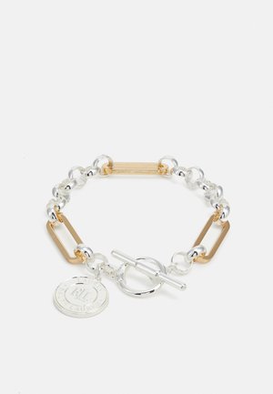 Bracelet avec maillons entrelacés en argent et or, fermoir rond à bascule, et pendentif circulaire gravé.