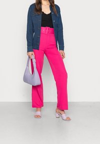 Jeansjacka, svart topp, rosa högmidjade byxor, lavendel-texturerad handväska och lila blockklackade sandaler med öppen tå.