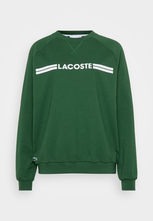 Felpa verde in misto cotone. Presenta una scollatura rotonda, maniche raglan e la scritta bianca "LACOSTE" con due strisce sul petto.