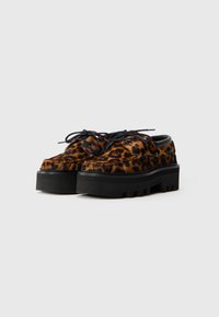 Sko med leopardprint og en sort struktureret sål, der har en rund tå, snørebåndsdesign og robust platformskonstruktion.
