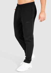 Zwarte sweatpants van zachte stof, met een elastische tailleband en zijzakken. Eenvoudig ontwerp met een subtiele logodetail aan de voorkant.