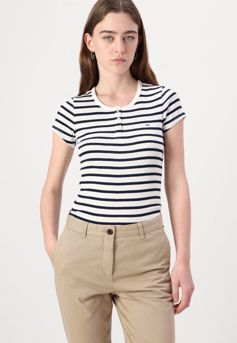Gestreiftes, geripptes T-Shirt in Weiß und Marineblau mit kurzen Ärmeln und Rundhalsausschnitt, ausgestattet mit drei Vorderknöpfen und einem kleinen Logodetail.