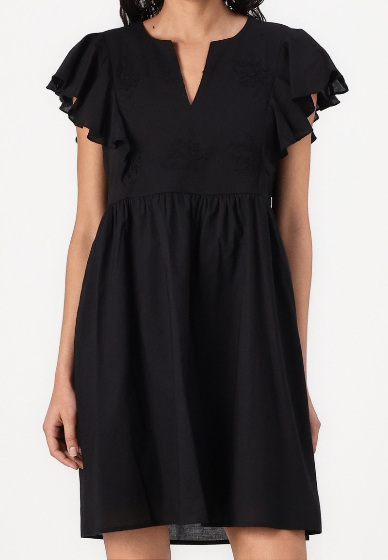 Robe noire courte avec manches courtes volantées, taille froncée, broderie florale subtile sur le corsage et décolleté en V.
