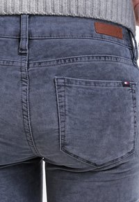 Mörk tvättade denimjeans med en slät textur, utrustade med en brun läderlogga och dubbelstickade bakfickor.