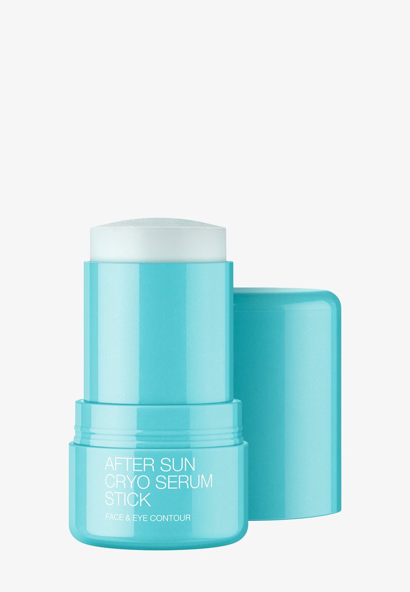 Contenitore cilindrico blu con bastoncino di siero solido bianco esteso, etichettato "After Sun Cryo Serum Stick Face & Eye Contour" senza il tappo.