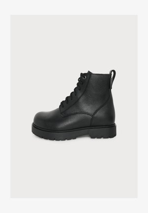 Bottine noire en cuir avec bout arrondi, laçage à l'avant, surface texturée, semelle épaisse crantée et languette à l'arrière.