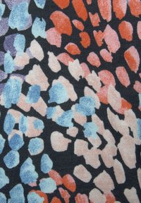 Textil mit schwarzem Hintergrund und mehrfarbigen Flecken in Rot, Pink, Blau und Lavendel. Glatte Textur mit einem Stoffmuster.