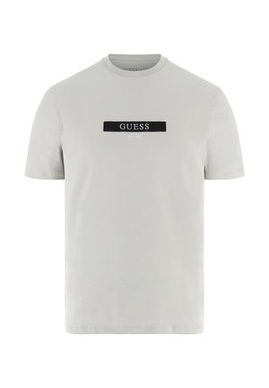 Lichtgrijs katoenen T-shirt met een ronde hals en korte mouwen, voorzien van een zwart rechthoekig label met het "GUESS EST. 1981" logo in witte letters.