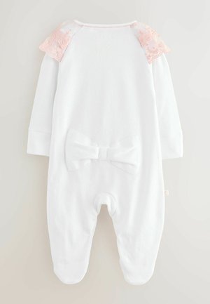Biela dlhá kombinéza s ružovým čipkovaným akcentom na pleciach a mašľou na chrbte. Mäkká tkanina so hladkým povrchom a dizajnom so zateplenými nožičkami.