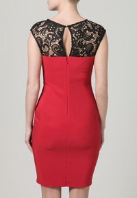 Czerwona dopasowana sukienka z czarną koronkową wstawką na plecach, bufiaste rękawy oraz otwarcie w kształcie klucza z tyłu. Gładka tekstura z zapięciem na zamek.