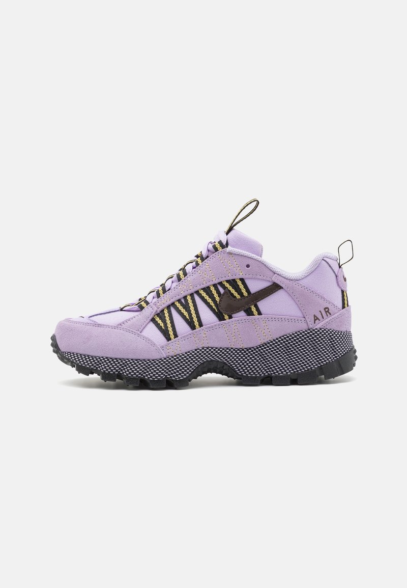 Chaussure de randonnée Nike Air lilas avec lacets rayés noirs et jaunes, swoosh noir, semelle noire épaisse et texturée, et languettes de traction sur la languette et le talon.