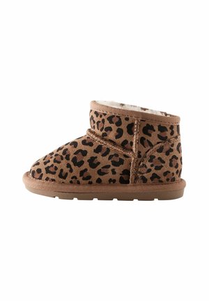 Leopardmönstrad ankelsko med en mjuk tanfärgad mocka utsida, fuskpälsfoder, rund tå och gummisula. Sömnadsdetaljer på sidan.