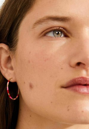 Barvni obročki za ušesa iz majhnih, valjastih perlic v rožnatih in rdečih tonih. Imajo tanek zlati žični zapiralni mehanizem.