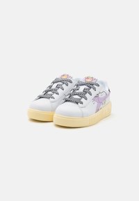Weiße Ledersneaker mit schwarz-weißen gemusterten Schnürsenkeln, lila Akzenten und einer cremefarbenen Sohle. Auf der Seite befindet sich ein Cartoon-Design.