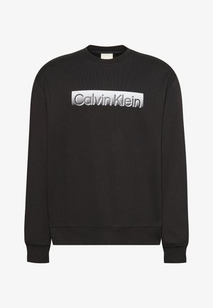 Sweat-shirt noir à manches longues avec le logo « Calvin Klein » blanc centré sur la poitrine, doté de poignets et d’un ourlet côtelés.