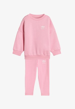 Ljusrosa träningsset bestående av en sweatshirt med rundad hals och sänkt axel samt matchande leggings, båda med en vit logotyp.
