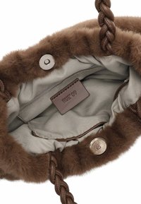 Binnenkant van een bruin faux fur handtas met een gevlochten bruine handvat, drukknoopsluiting en lichtgrijze voering. Bevat een bruine label met "RUE 09."