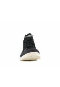Zapatilla alta negra con suela de goma texturizada, suela blanca contrastante y cordones negros. Logotipo visible en la lengüeta.