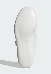 Hvid sneaker sål med en tekstureret overflade, der har en glat afrundet front og mønstret greb. Inkluderer en sideudskæringsdetalje.