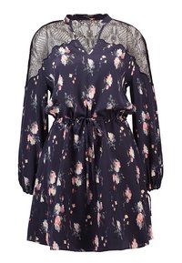 Robe bleue marine à fleurs avec manches longues, détails en dentelle sur les épaules, taille élastique et ceinture à nouer. Elle offre une coupe décontractée et une jupe légèrement froncée.