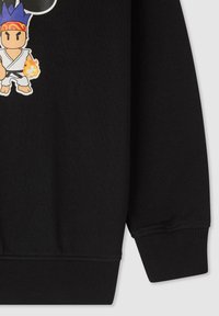 Manica di felpa con polsino a coste, che presenta un personaggio dei cartoni animati con capelli blu, fasciatura, abbigliamento da karate e un pugno infuocato su tessuto nero.